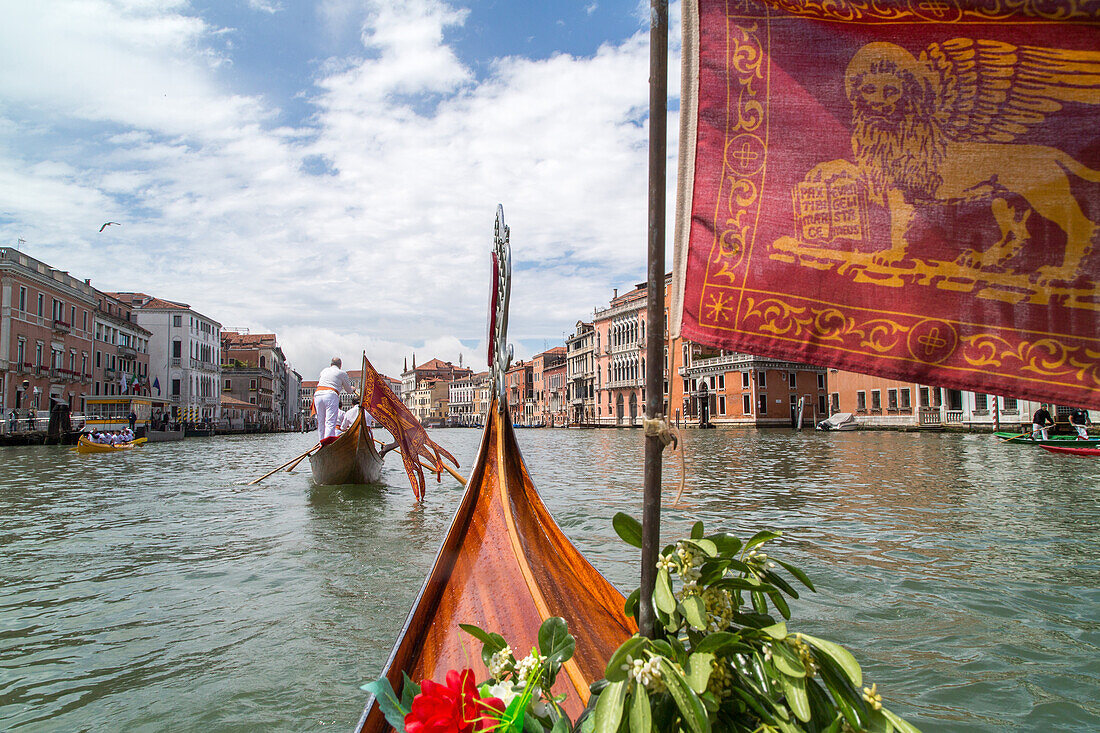 Blick über Gondelspitze und rote Flagge der Serenissima mit dem Löwen von San Marco, Venedig, Italien