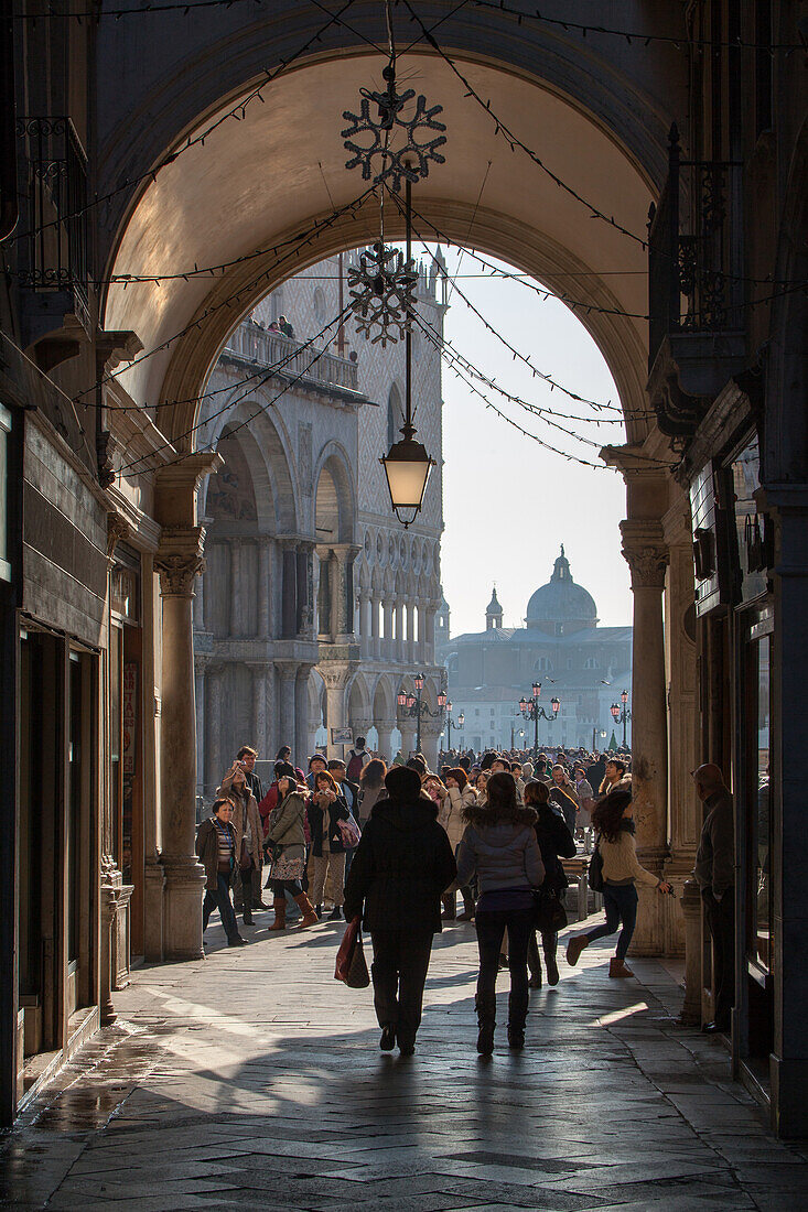 view through arcade towards St Mark's Square, San Marco, back lighting, silhouettes of people, tourists, Venice, Italy