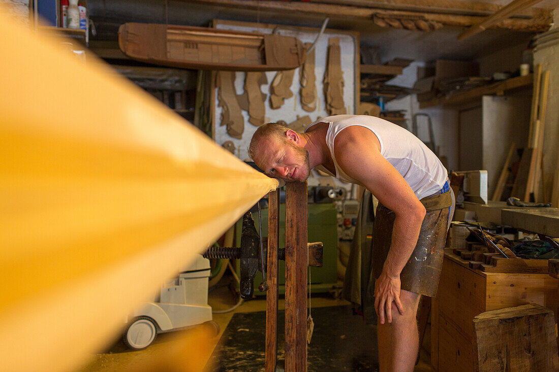 assistant Pietro Meneghini inspects a timber oar in the workshop of Venetian forcola and oar maker Saverio Pastor, craftsman, art object, Venice, Italy