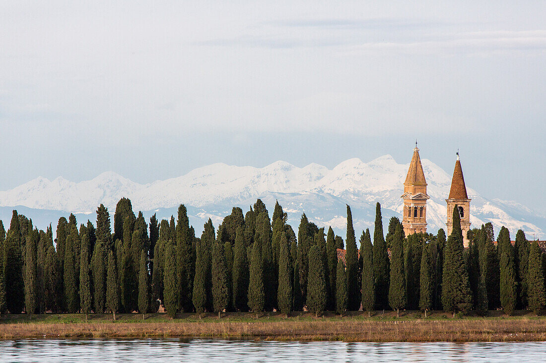Monastery Island of San Francesco del Deserto, surrounded by cypresses, background snow covered Alps, Venice, Italy