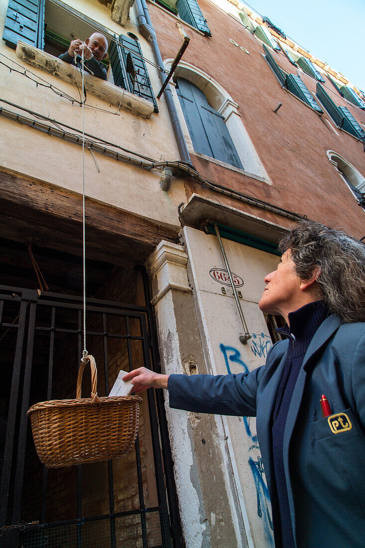 Postwoman, post, places mail in basket lowered from upstairs, senior citizen, service, curiosity, Venice, Italy