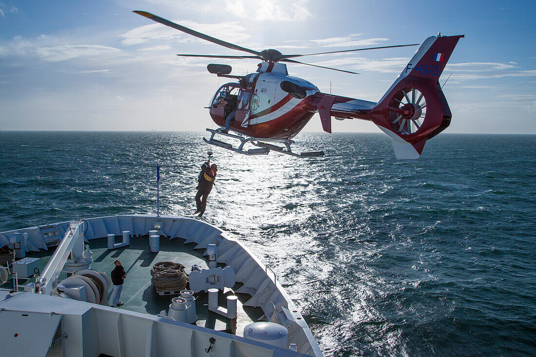 Ein Hubschrauber zieht den Lotsen des Hafens Dünkirchen von Deck am Bug von Kreuzfahrtschiff MS Deutschland (Reederei Peter Deilmann), Nordsee, nahe Frankreich, Europa