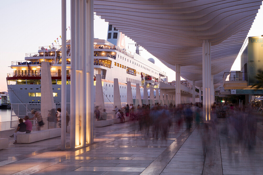 Long exposure of people walking past Malaga Cruise Terminal and cruise ship MS Deutschland (Reederei Peter Deilmann) at dusk, Malaga, Andalusia, Spain