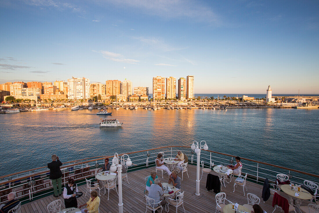 Passagiere genießen ihr Abendessen an Deck vor dem Lido Café von Kreuzfahrtschiff MS Deutschland (Reederei Peter Deilmann) bei Sonnenuntergang, Malaga, Andalusien, Spanien, Europa