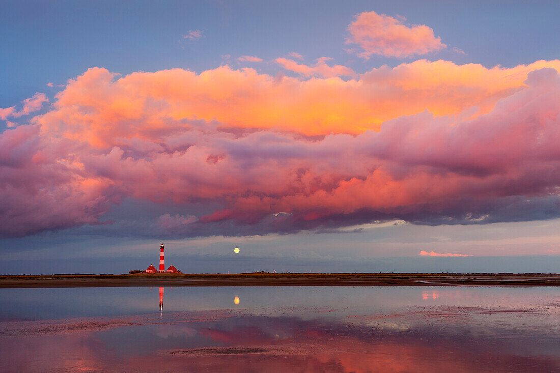Lighthouse, clouds and moon reflecting in the flats near Westerhever lighthouse, Eiderstedt peninsula, Schleswig-Holstein, Germany
