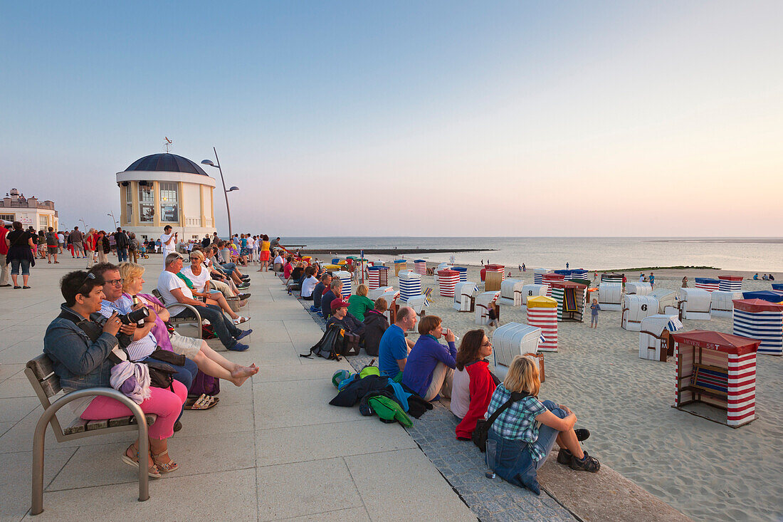 People on the beach promenade watching the sunset, Borkum, Ostfriesland, Lower Saxony, Germany