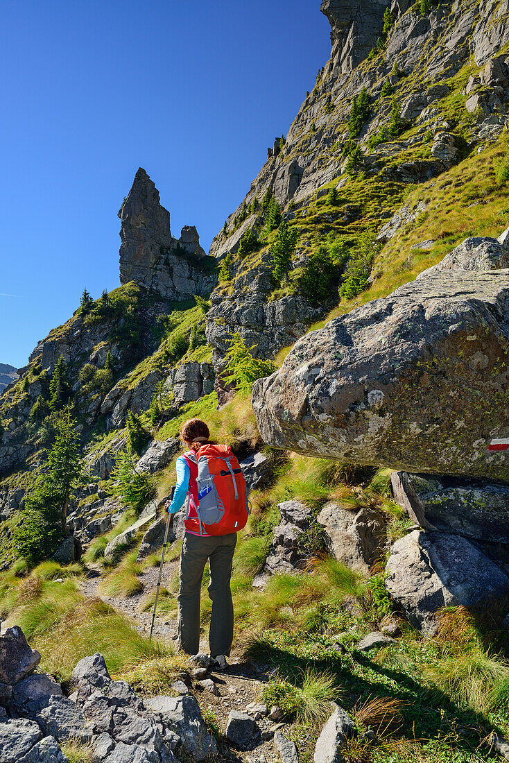 Woman hiking on path towards rock spire, Trans-Lagorai, Lagorai range, Dolomites, UNESCO World Heritage Site Dolomites, Trentino, Italy