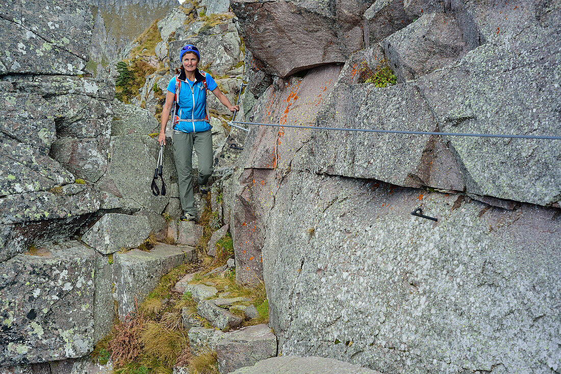 Woman hiking on fixed rope route between boulders, Trans-Lagorai, Lagorai range, Dolomites, UNESCO World Heritage Site Dolomites, Trentino, Italy