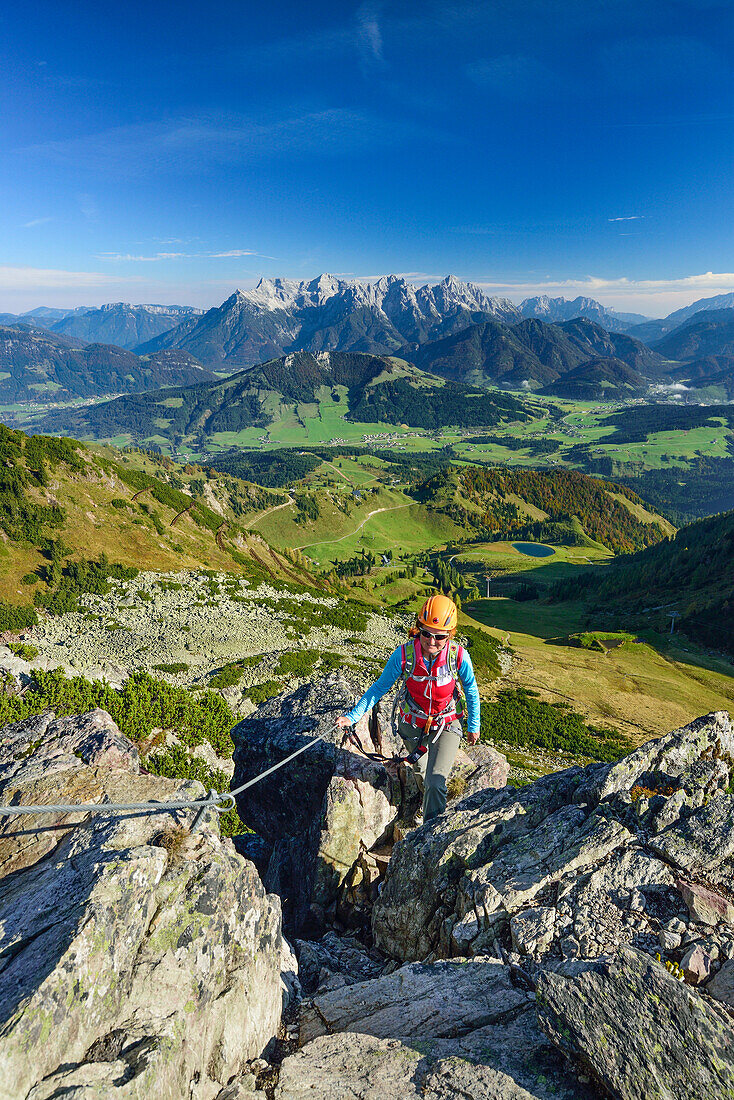 Woman ascending fixed rope route, Loferer Steinberge range in background, fixed rope route Henne, Henne, Kitzbuehel range, Tyrol, Austria