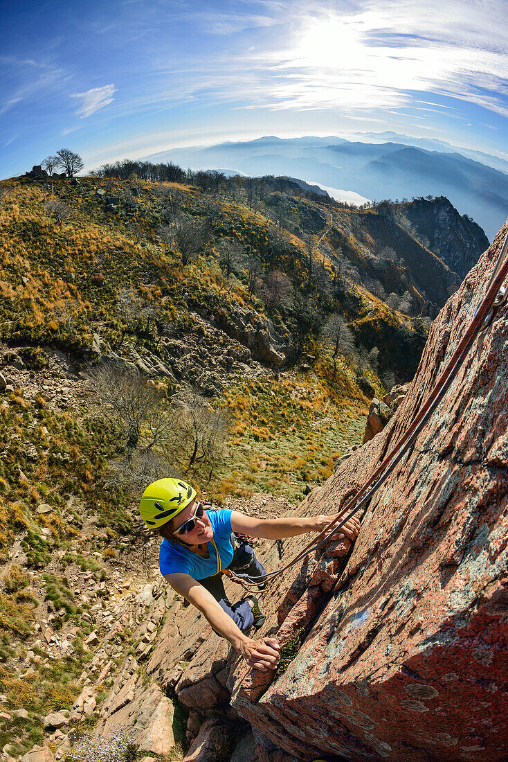 Woman climbing on red Granite rock, Mottarone, Piedmont, Italy