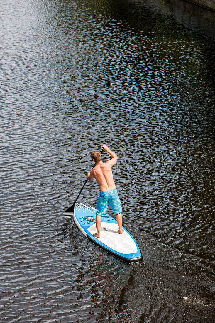 Man stand up paddling on the river Alster, Hamburg, Germany