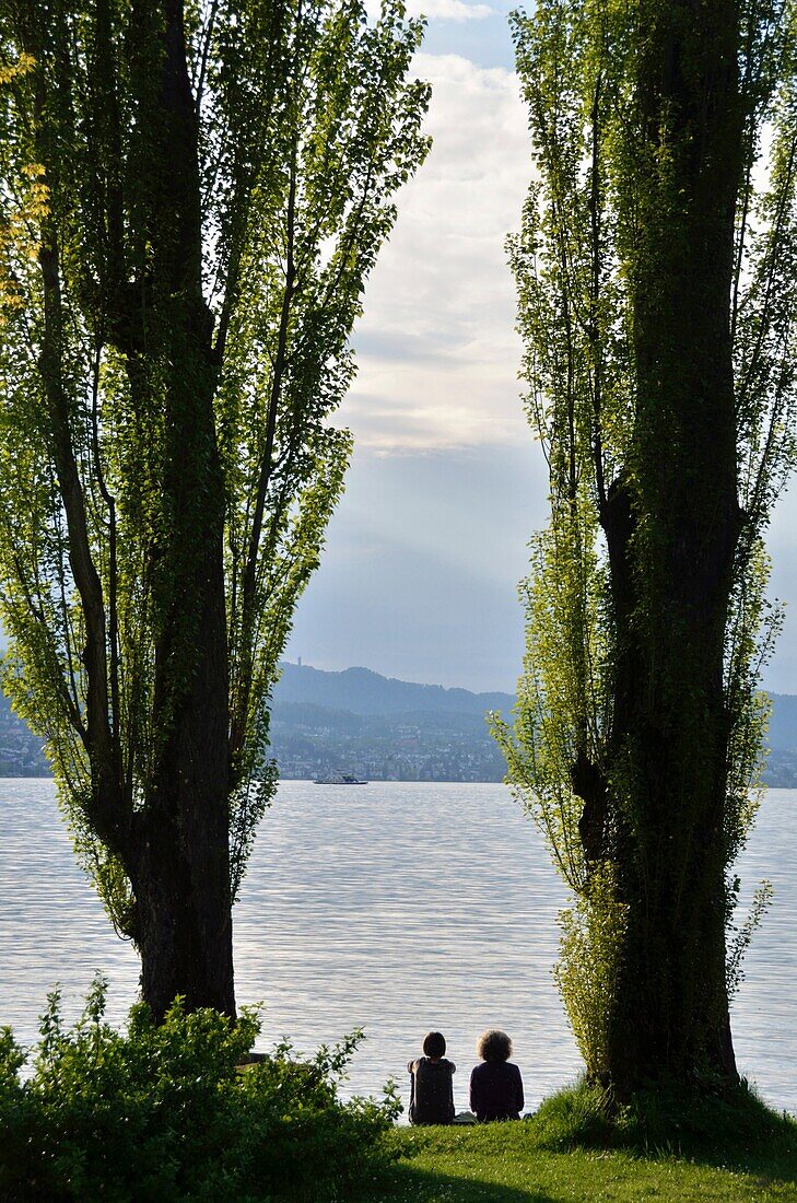 Two women sitting next to Lake Zurich at Au, Switzerland.