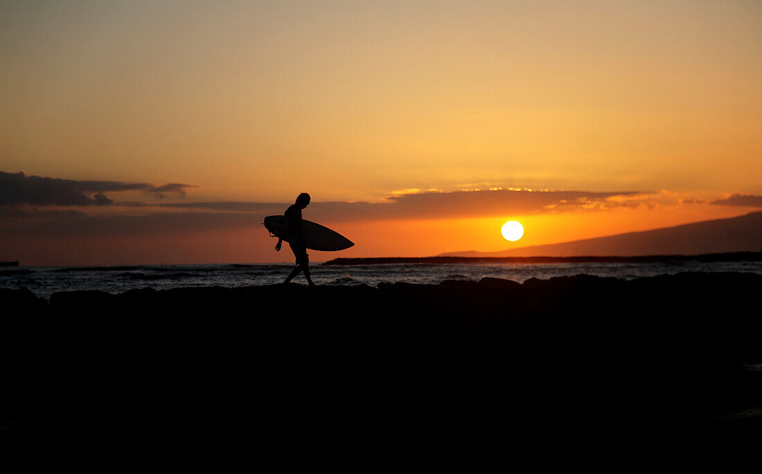 Hawaii, Oahu, Waikiki, Silhouette Of A Surfer Walking On A Rock Wall At Sunset