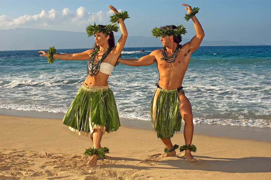 Male And Female Hula Dancers In Ti-Leaf, Haku, Lei, In A Dancing Pose On The Beach