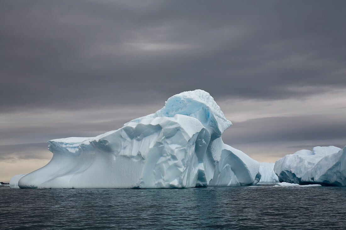 Gigantic Icebergs Adrift In Waddington Bay Against A Cloudy Sky, Antarctica