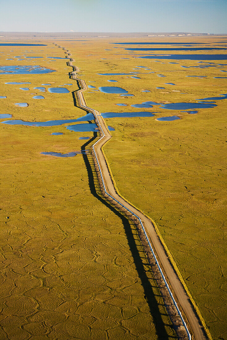 Aerial View Of Oil Gathering Lines Alongside A Dirt Road At Prudhoe Bay's Kuparuk Field In Alaska