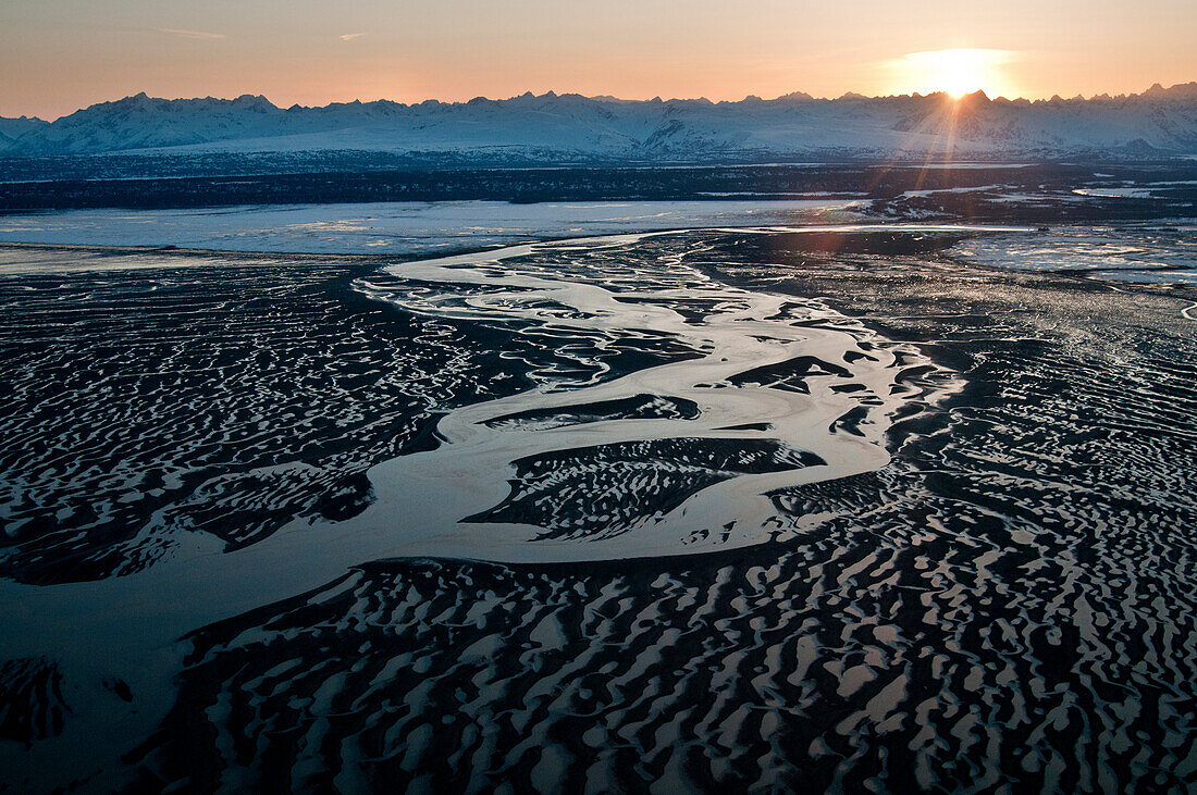 Aerial Evening View Of The Chakachatna River And Mudflats Of Cook Inlet With The Sun Setting Behind The Alaska Range, Southcentral Alaska, Winter