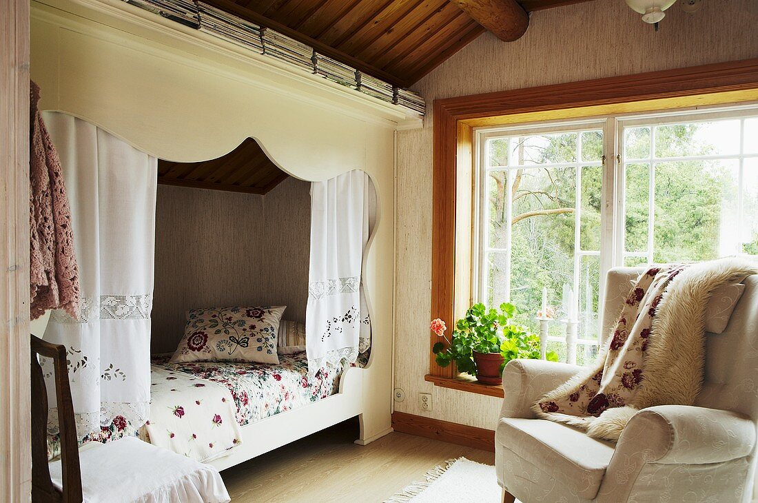 An alcove and an armchair in the attic room of a country house with windows