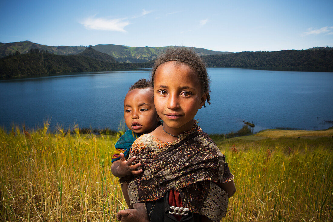 'Young girl with baby on her back in wheat field, Wenchi crater and lake, to the West of Addis Ababa; Ethiopia'