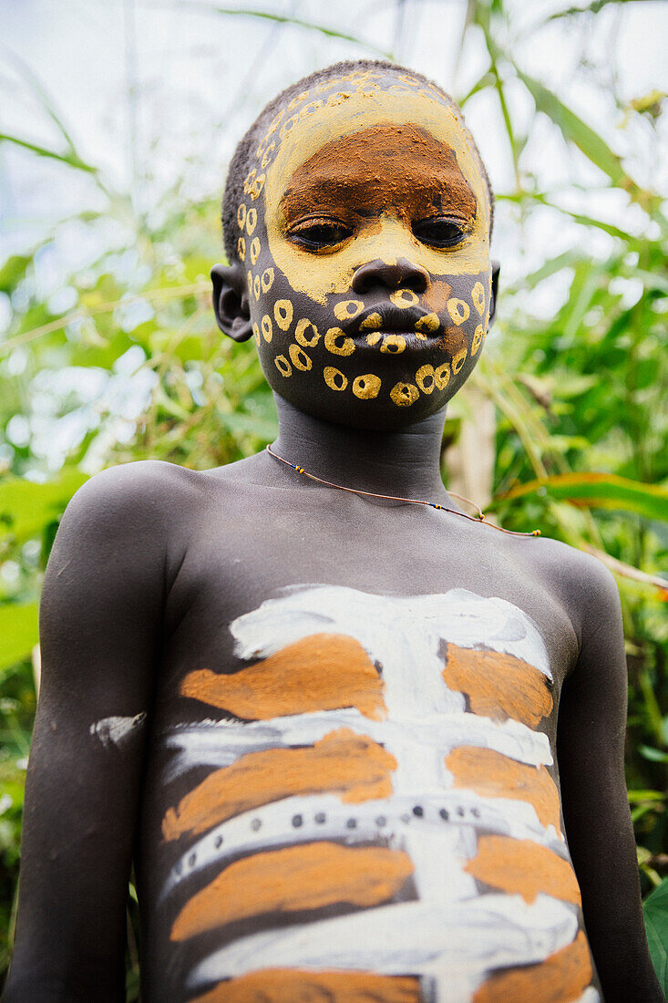 'Surma child with face painted with pigment made from powdered coloured stones, Omo region, Southwest Ethiopia; Kibish, Ethiopia'