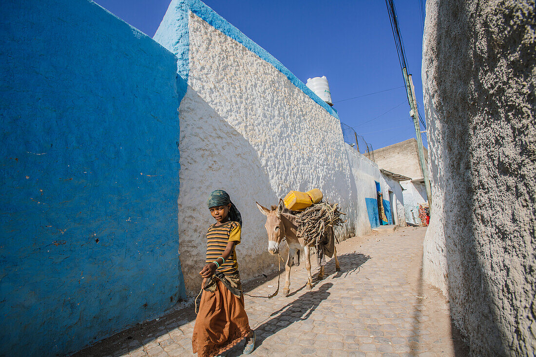 'A young girl walking through the colourful streets of the old City of Harar in Eastern Ethiopia; Harar, Ethiopia'