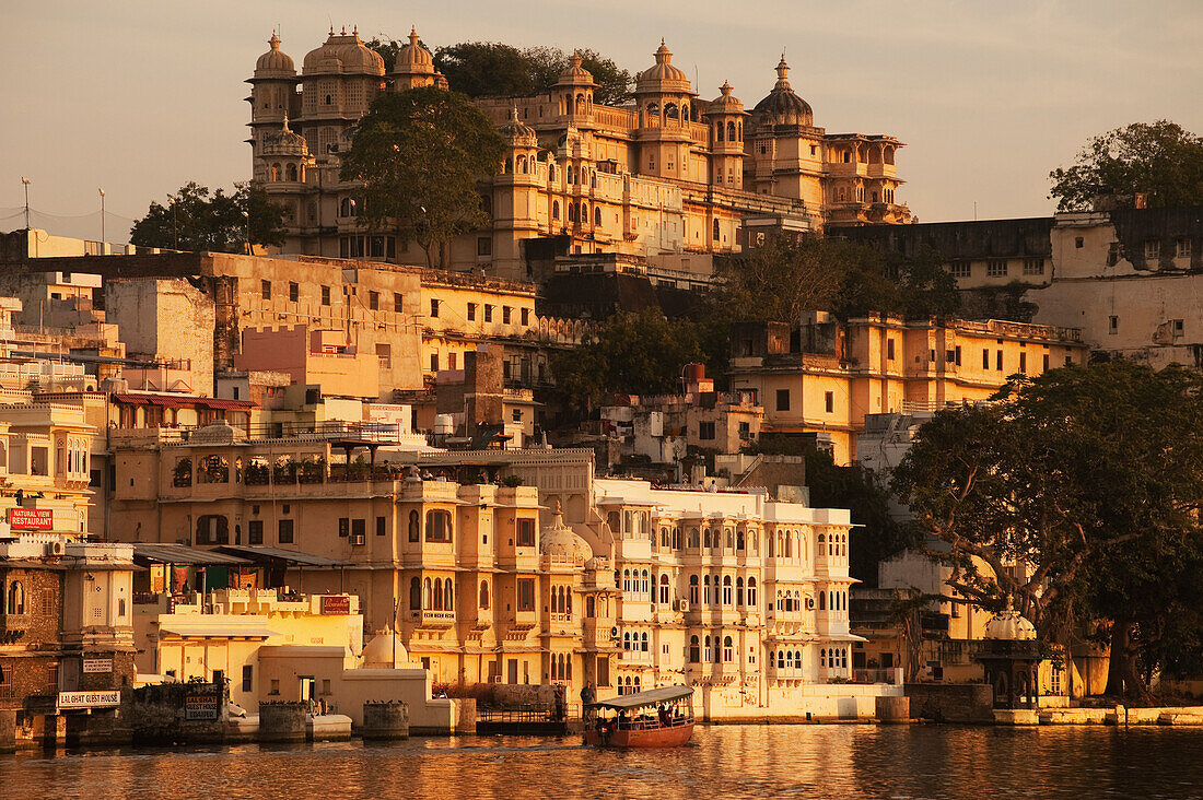 'Buildings glowing in the sunlight of the setting sun along the river; Udaipur, India'