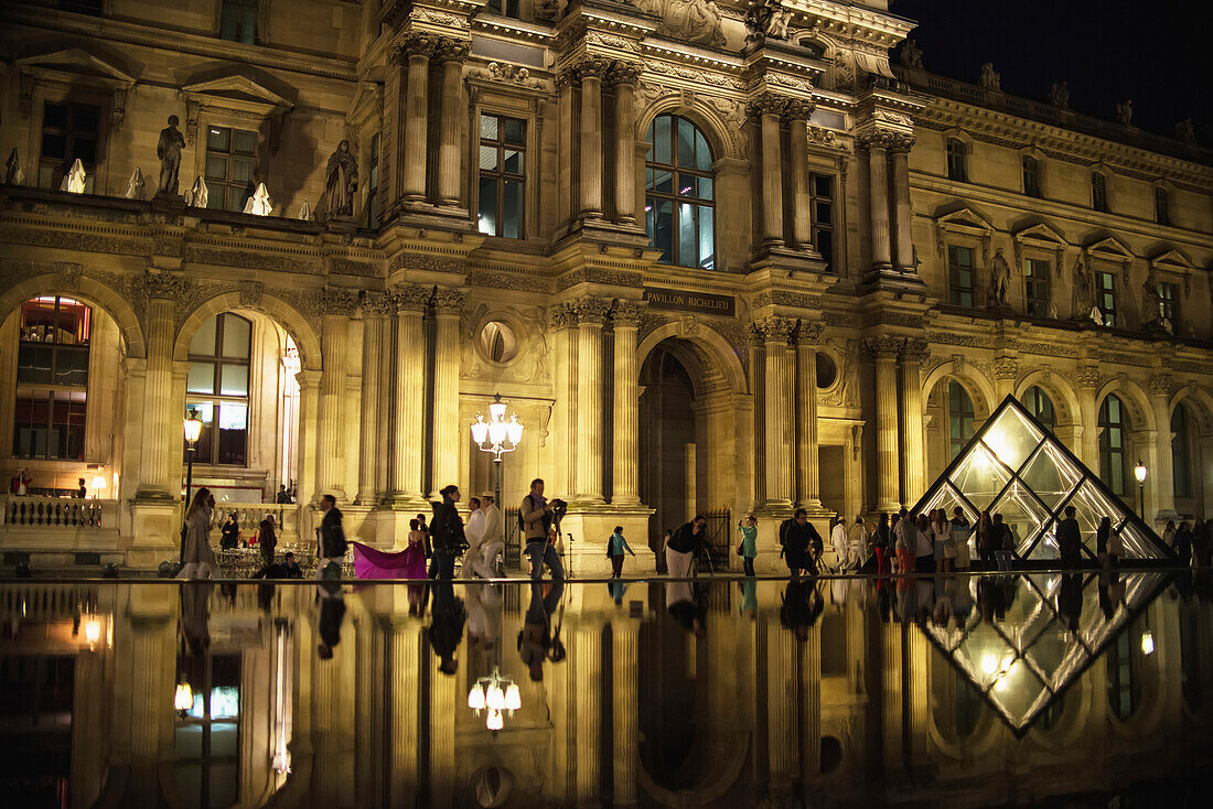 'Tourists are reflected in the pools out the front of The Louvre Museum; Paris, France'