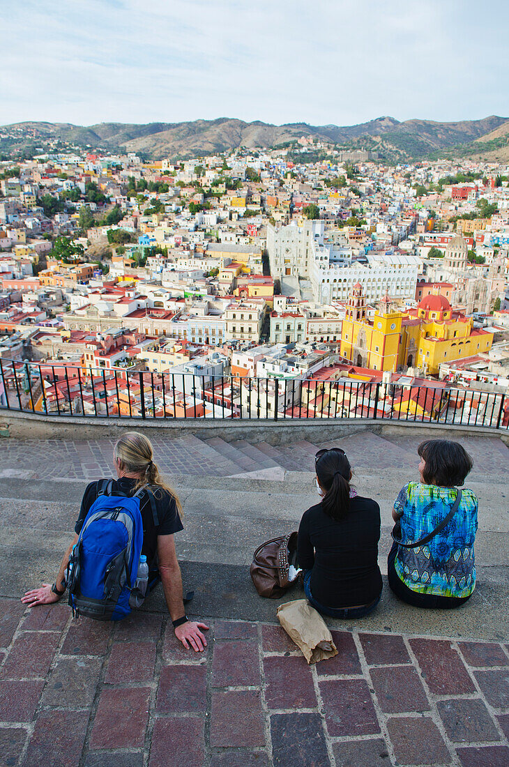 'Three people sit viewing the cityscape of Guanajuato; Guanajuato, Mexico'