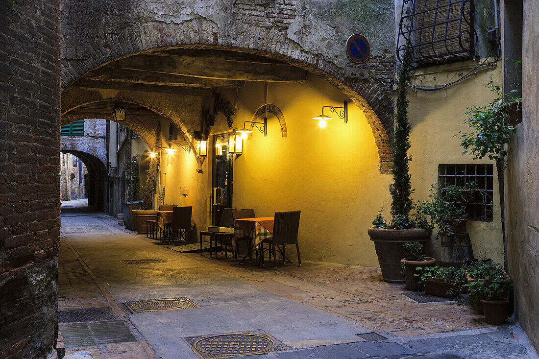 'Seating along a wall illuminated by golden light under a covered walkway; Montepulciano, Tuscany, Italy'