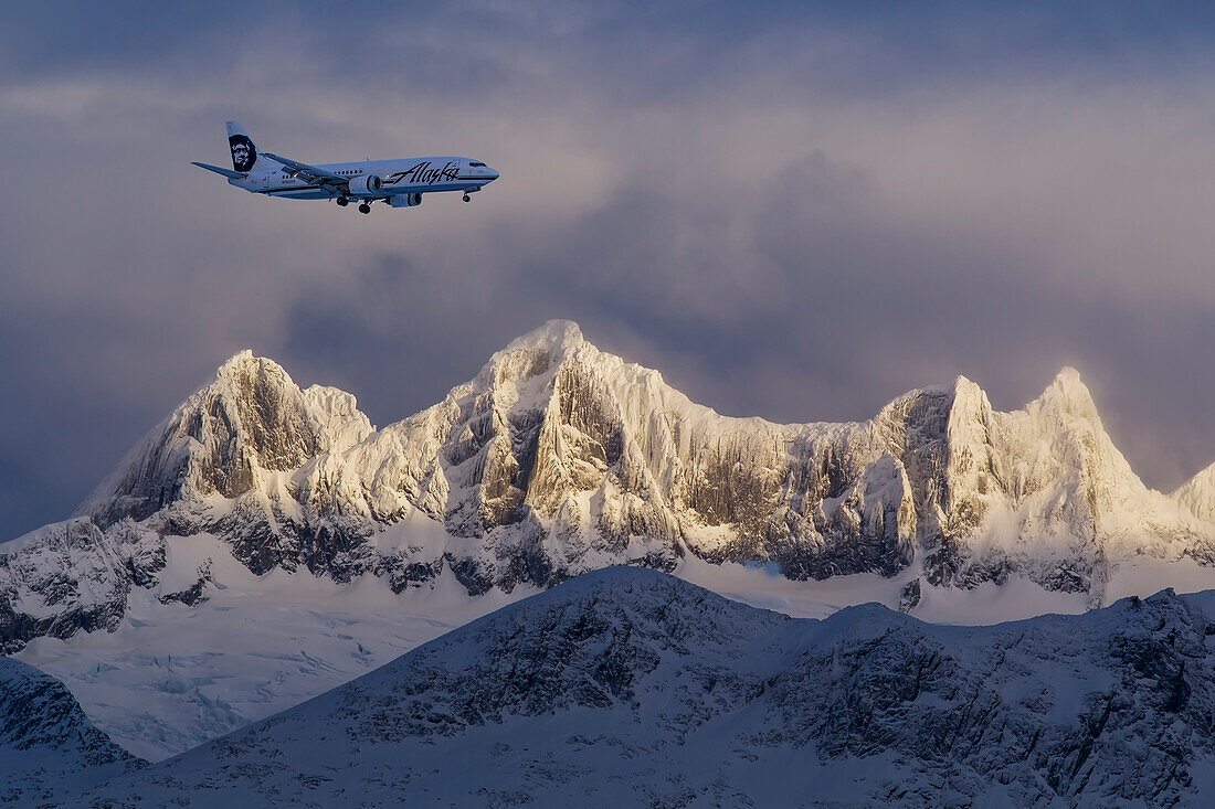 An Alaska Airlines jet on approach to Juneau International Airport passes by Mendenhall Towers, Winter,Tongass National Forest, Juneau, Alaska.