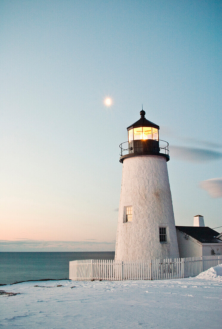 Pemaquid Point lighthouse catches the first rays of the morning sun as the moon sets beyond.