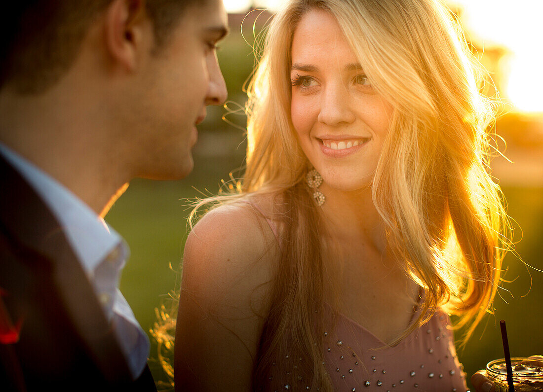 A pretty young girl stares at the eyes of a smart young man stands close to her.