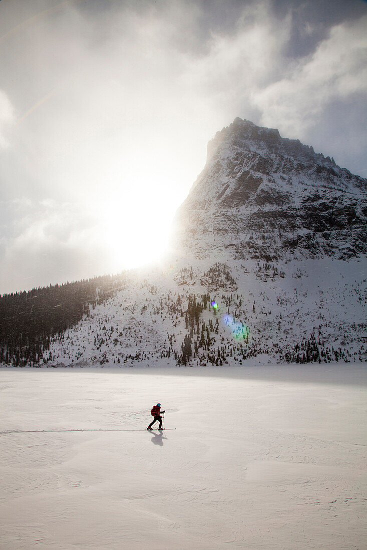 A woman skiing on Two Medicine Lake in front of Sinopah Mountain in Glacier National Park, Montana.