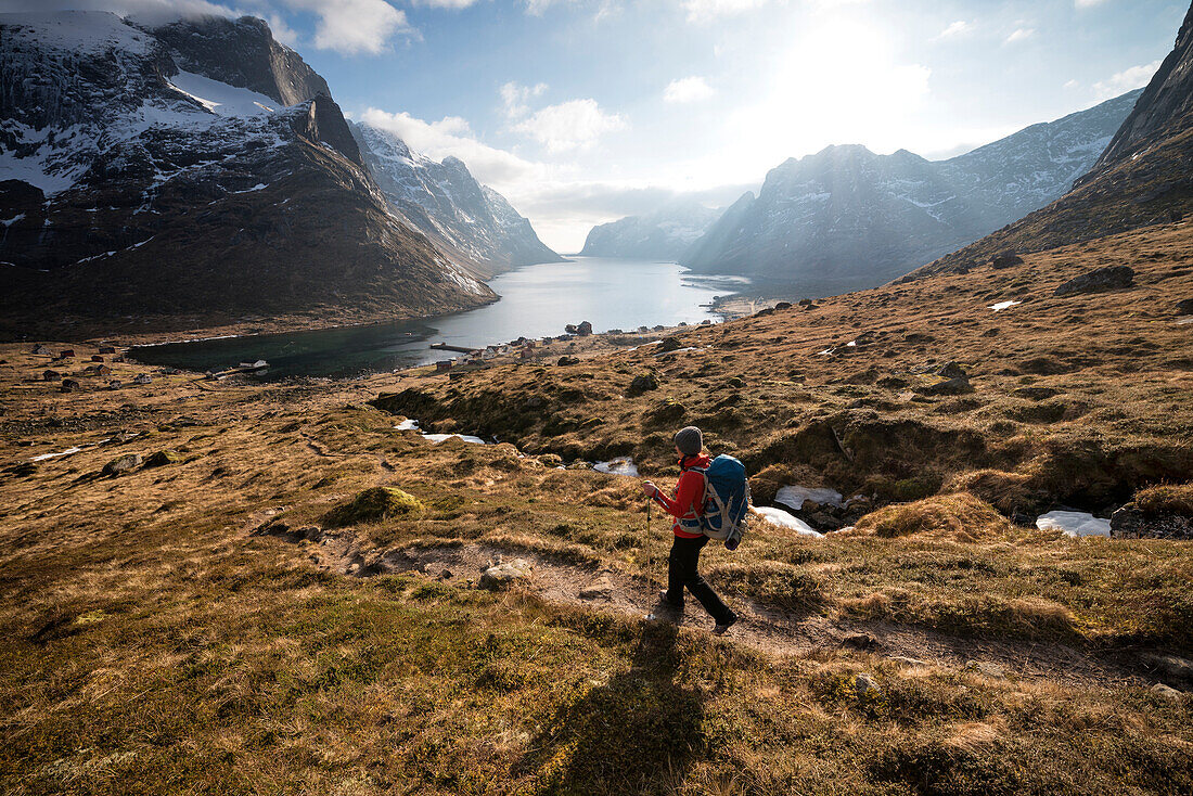 Female hiker descending trail to catch ferry at village of Kjerkfjord, Moskenes??y, Lofoten Islands, Norway