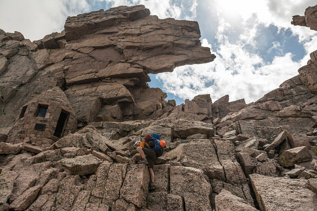 A man hiking through the granite formation known as the Keyhole route on Long's Peak in the  Rocky Mountain National Park, Estes Park, Colorado.