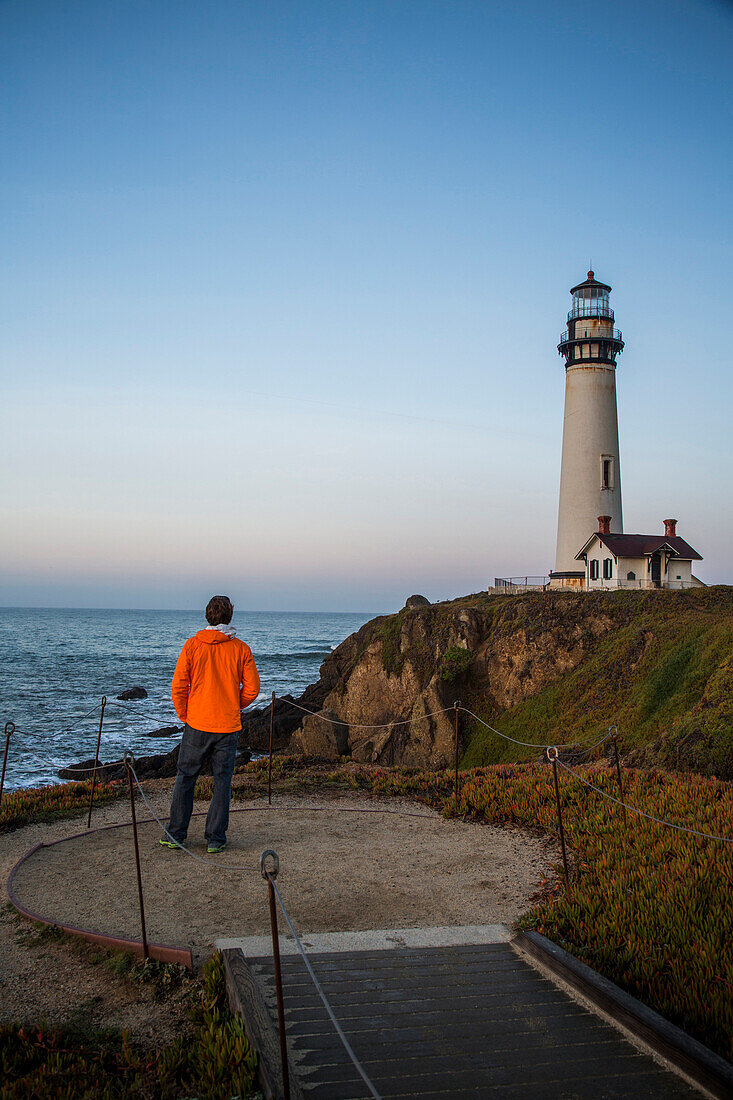 A man enjoys the dusk views at the Pigeon Point Lighthouse near Pescadero, California on a sunny day.