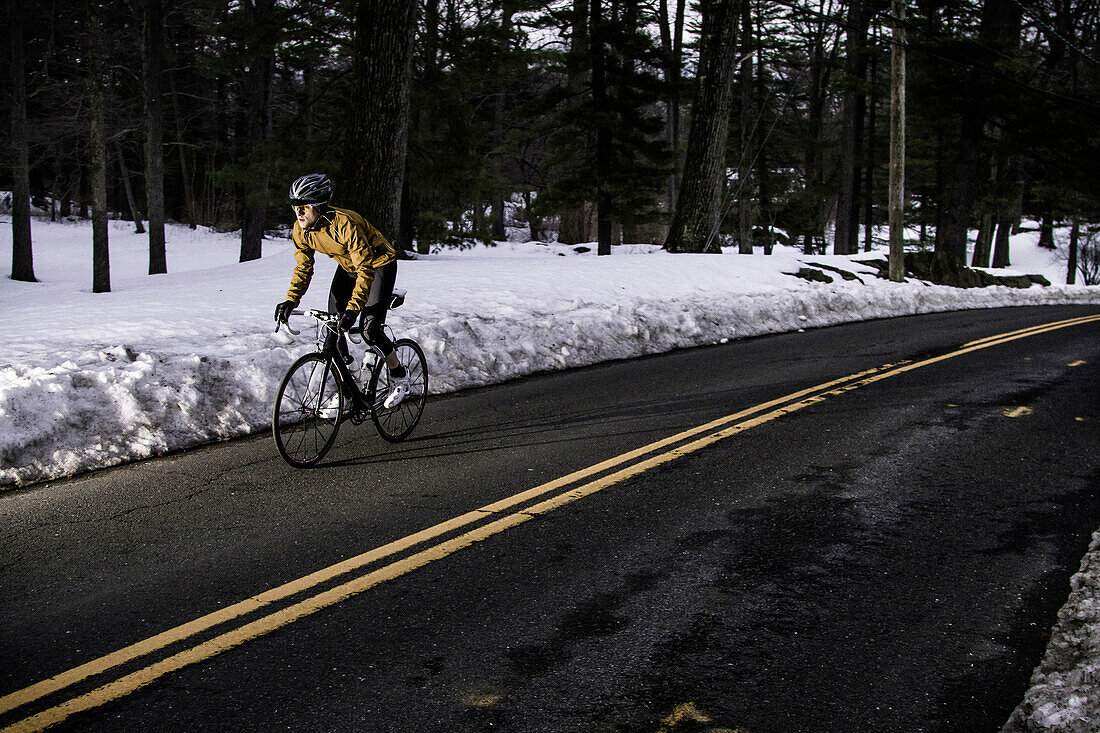 A road cyclist rides through a wintery landscape.