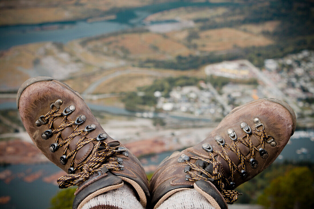A hiker dangles their boots over the edge of the Chief Mountain in Squmish, BC, Canada.