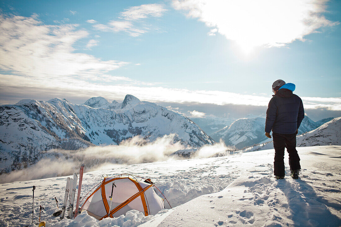 A man stands on Llama Peak above his tent in British Columbia, Canada.