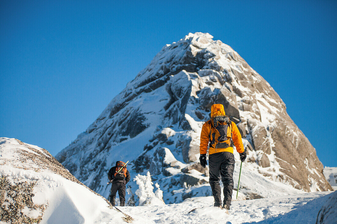 Two backpackers approach a summit block in the Coquihalla Recreation Area of British Columbia, Canada.