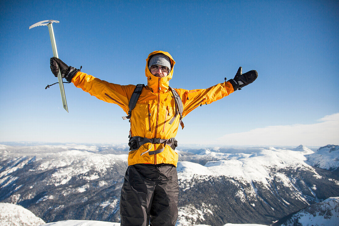 Portrait of a climber on mountain summit during winter in the Coquihalla Recreation Area of British Columbia, Canada.