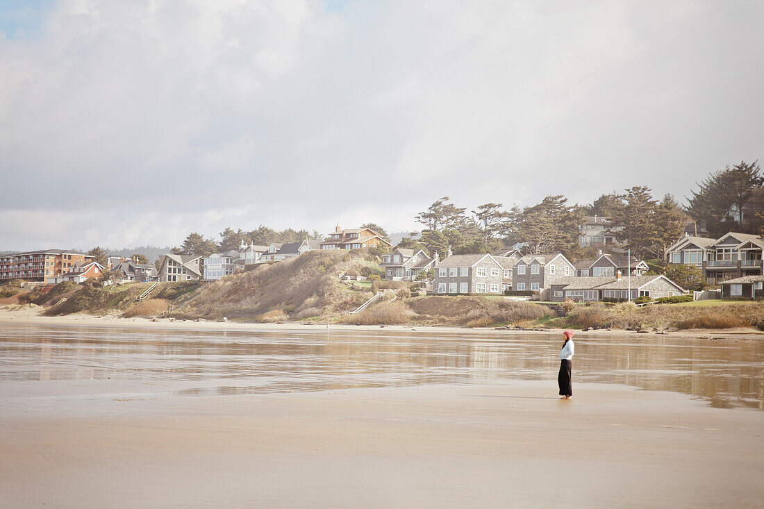 A young woman walks on a large sandbar at Cannon Beach, Oregon.