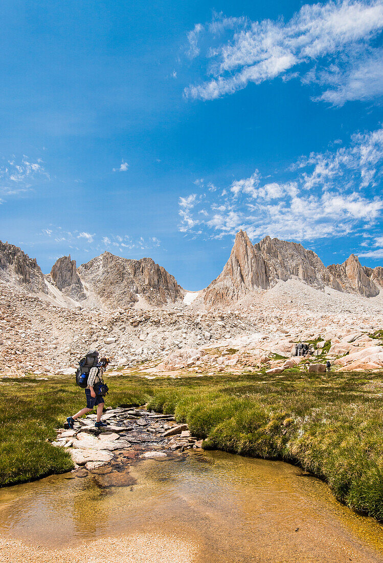 Backpacker crosses creek in the Granite Park