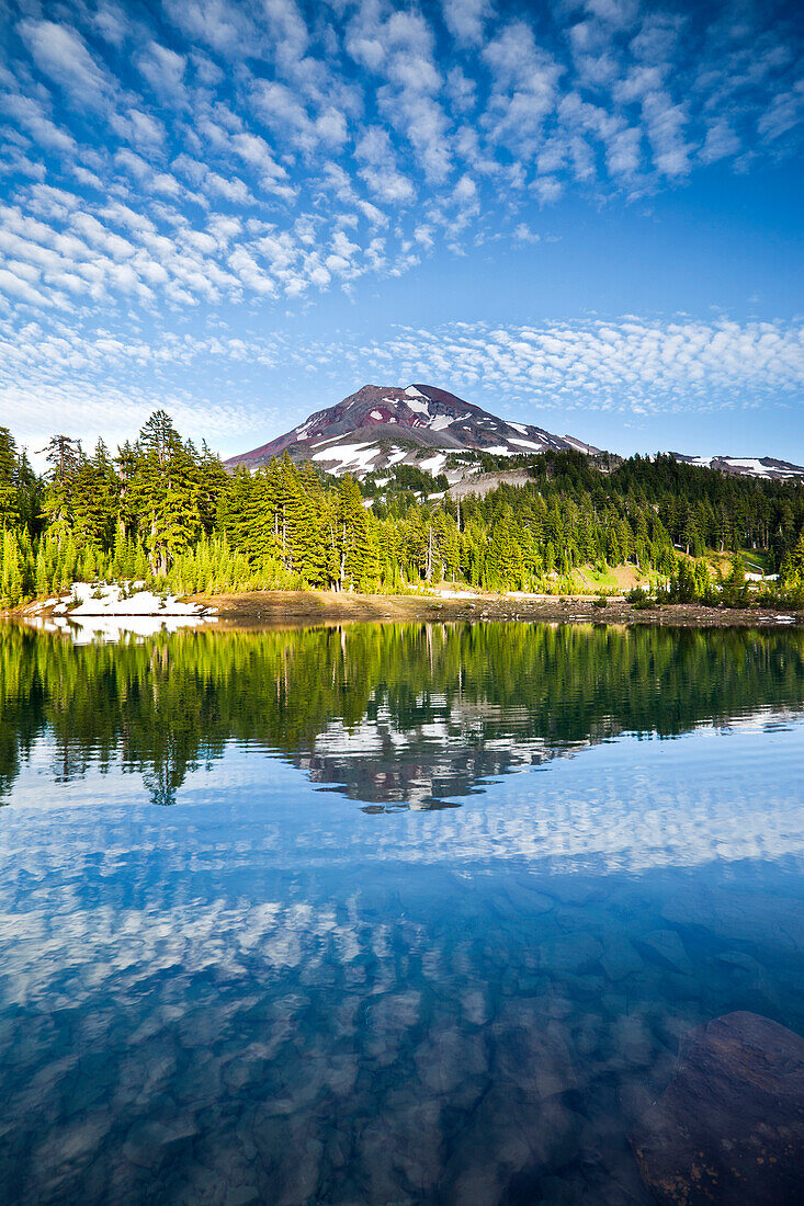 South Sister, a volcanic peak part of the Cascade Range, is reflected in a small apline lake.