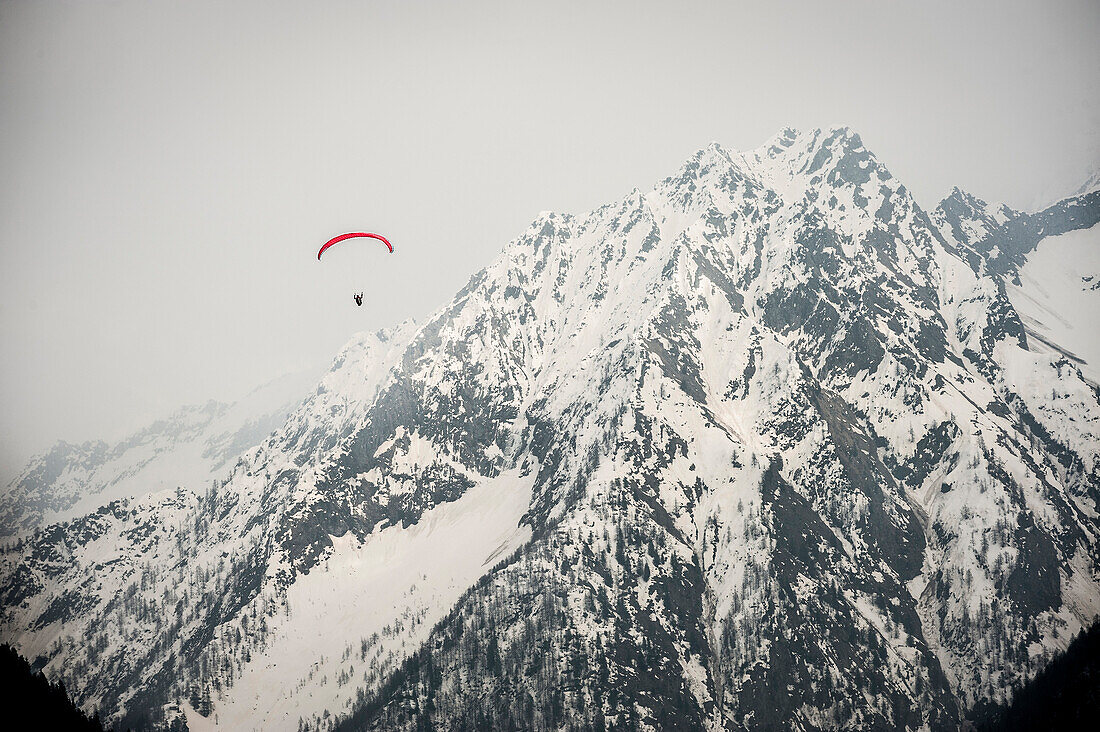 Paraglider flying down from Monte Rosa. Macugnaga, Ossola, Italy.