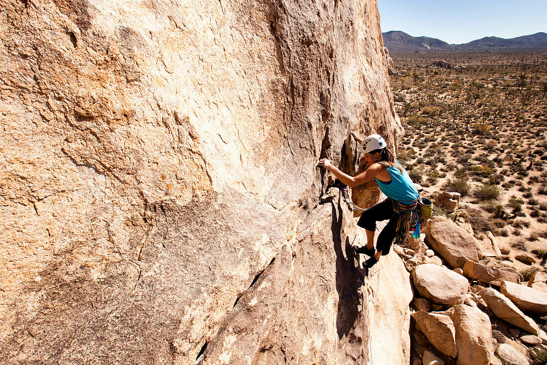 A female climber works her way up Sidewinder (5.10b) in Joshua Tree National Park, California.