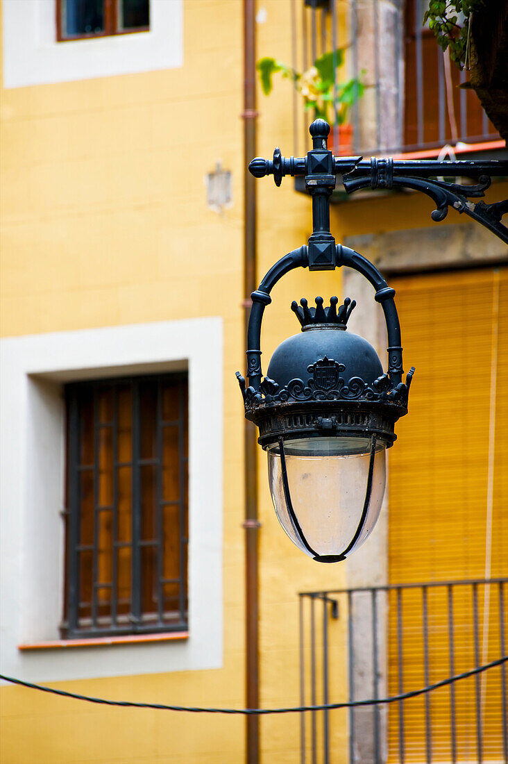 'An ornate lamp hanging from a building; Barcelona, Spain'