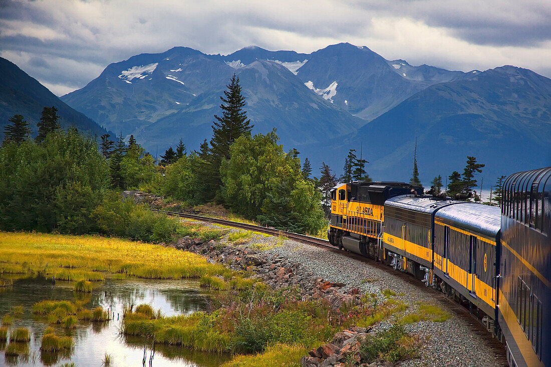 View Of An Alaska Railroad Train Travelling Between Anchorage And Seward Along Turnagain Arm In Southcentral Alaska, Summer