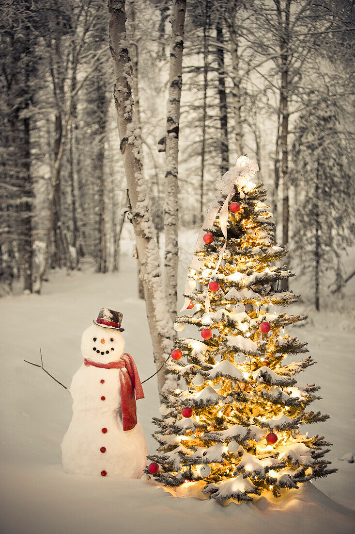 Snowman With Red Scarf And Black Top Hat Standing Next To A Christmas Tree In Snow Covered Birch Forest, Winter