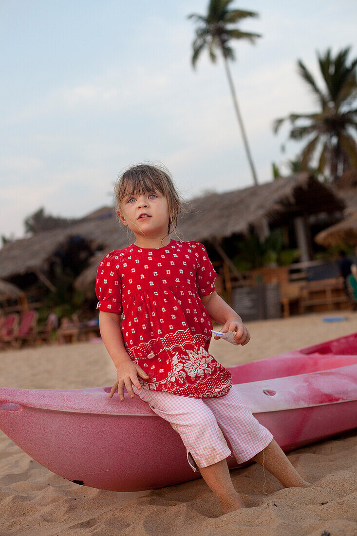 Kiki Lett aged 5 sits on a canoe, Patnum Beach, Goa, India.